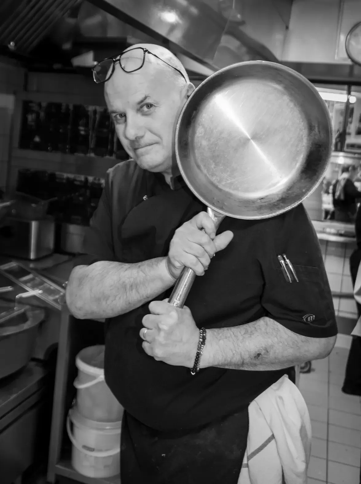 Frédéric en cuisine, une poêle à la main (photo noir et blanc)